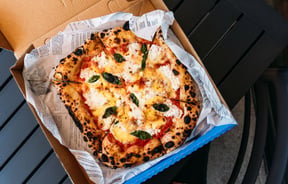 A close up of a delicious looking pizza in a blue box.