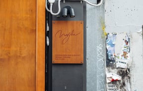 A wooden sign with information on Bar Magda.