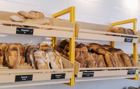 Close up of rows of sourdough on wooden shelves attached to a wall at Bellbird Bakery in Christchurch.