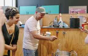 A person in a white t-shirt sprinkling baking soda into a brewing canister.