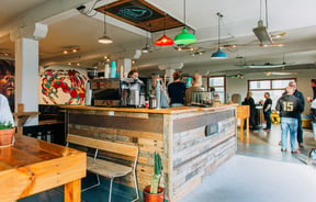 Interior view of the cafe with people standing around at Escape Coffee Roasters, New Plymouth.