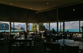 Inside the restaurant where people are dining and looking out the windows over the lake.