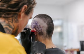 Man getting his head tattooed.