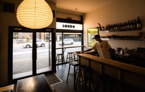A man placing a plate of food on the counter at Londo in Christchurch.