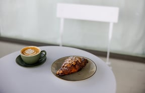 A coffee and croissant on a table.