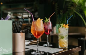 Three different cocktails on a black table with straws.