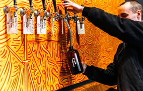 Man filling up a rigger with backdrop of psychedelic orange swirls at Monkfish, Wellington.