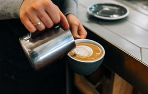 Pouring steamed milk into coffee cup at Ozone Coffee Roasters, New Plymouth.