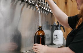 Woman pouring a beer at taps.