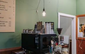 The coffee machine inside Tasteology with take away cups stacked on the top.