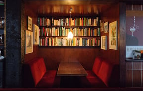 A booth beneath a shelves of books at The Library bar Wellington.
