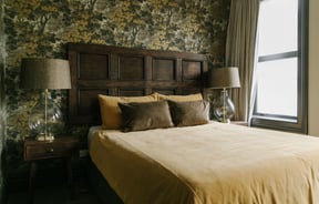 A bed dressed green and yellow in pillows and duvet cover inside The Old Confectionery Oamaru.