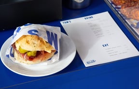 A sandwich and menu sitting on a blue table.