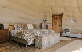 A bedroom set inside a Glamping pod with a wooden panelled floor.