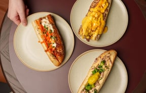Three delicious looking hot dogs on a table.