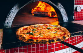 A pizza coming out of a hot oven.