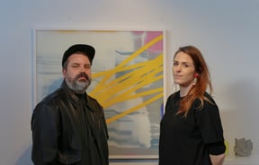 Nathan and Jen Ingram standing in front of an artwork in their gallery, Fiksate.