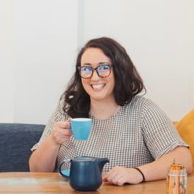 A woman holding a cup of coffee and smiling.