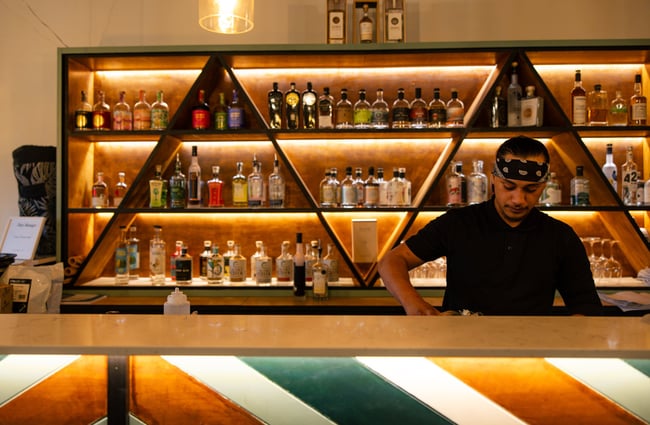 A man wearing a bandana working behind a bar.