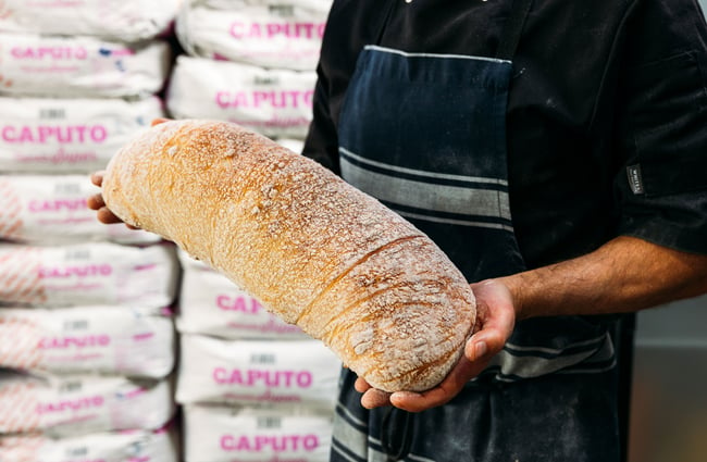 A man holding a loaf of baked bread.