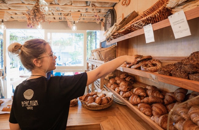 A staff member reaching for a large pretzel from a shelf.