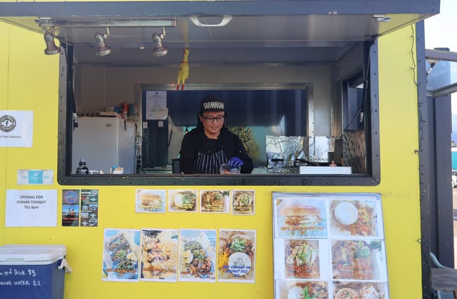 A person working in a yellow food cart.