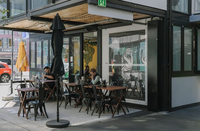People dining in the shade of a cantilevered floor in BOXed Quarter in Christchurch.