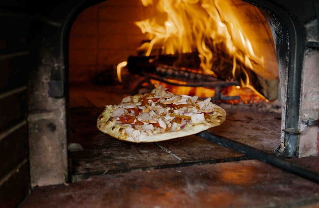 A pizza is paddled into the wood-fired oven at Brew Moon.