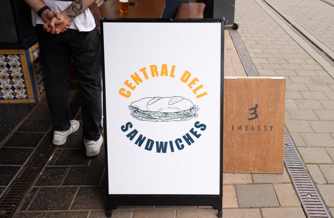 A Central Deli Sandwiches sign on a street.