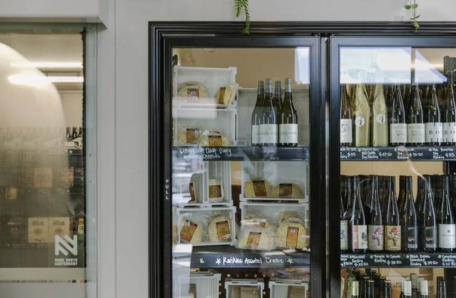 A close up of a fridge with wine and cheese on display.