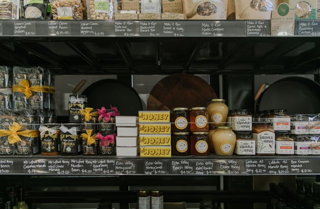A close up of honey products on display on black shelves.