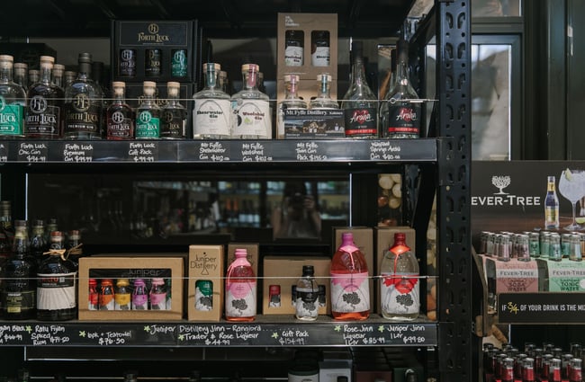 A close up of bottles of gin on display on black shelves.