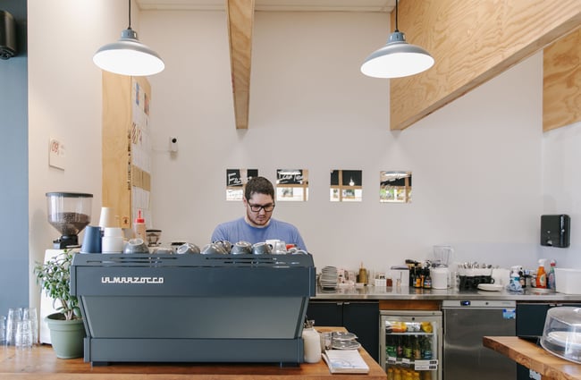 Man making coffee behind blue coffee machine at Dispense Espresso in Christchurch.