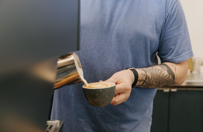 Man pouring hot milk into a cup at Dispense Espresso in Christchurch.