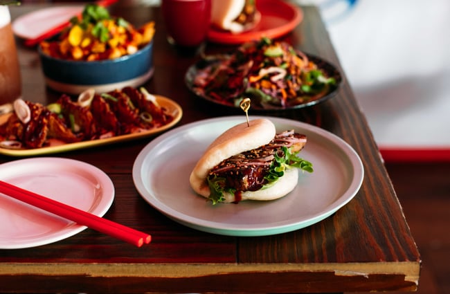 A close up of a bao bun and other dishes on the table at FunBuns.