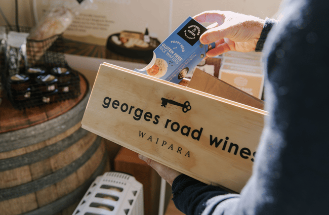 Worker packing a wooden gift box with the Georges Road Winery logo on it.