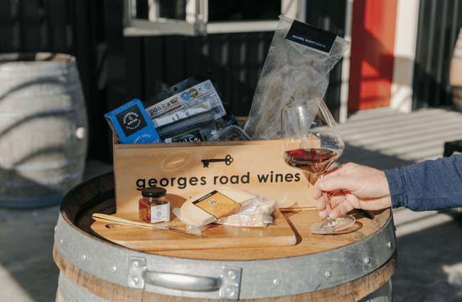 Winery gift box with cheeses and a glass of wine on a barrel.