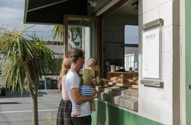 A couple and their small child look at the goods in the cabinet at Grizzly Baked Goods in Christchurch.