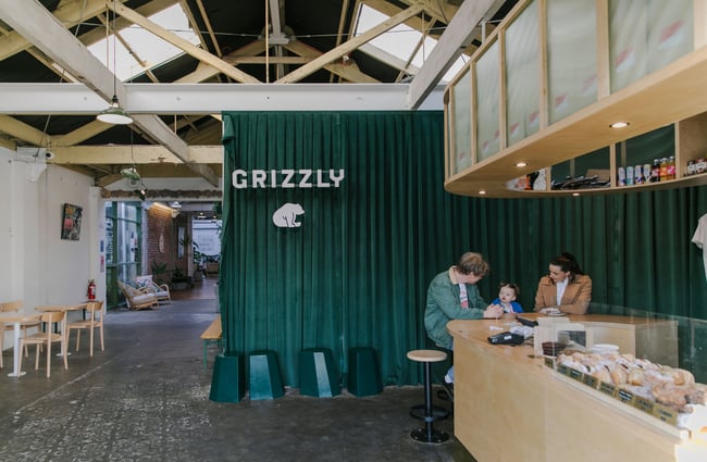 Interior view of a green velvet curtain with whit Grizzly logo.