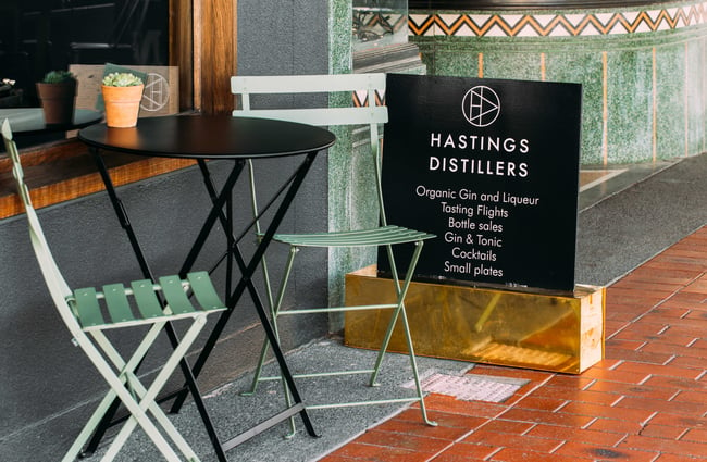 A small table and chairs out front of Hastings Distillers.