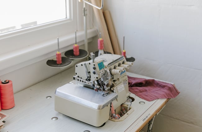 A close up of an overlocker sewing machine on a table.