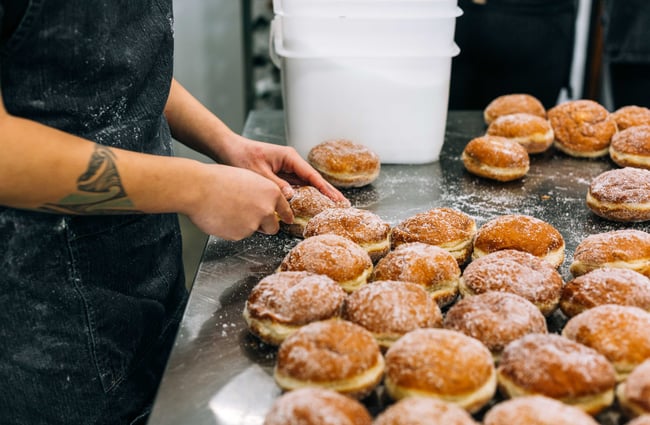 Person slicing open donuts ready to be filled at Knead Artisan Donuts, New Plymouth.