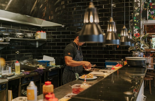 A chef working in the open kitchen at Little Pom's