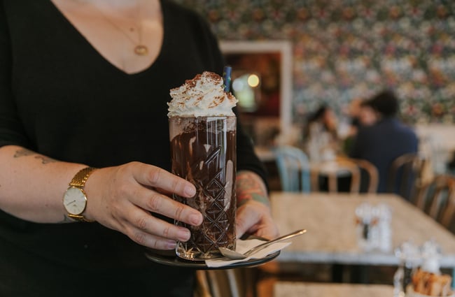 A close up of a person holding a large chocolate drink.