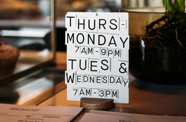 A black and white sign promoting the cafe's hours.