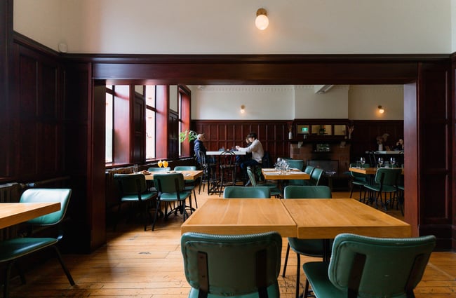 From one empty dining room to the other where people are sitting at a high table in the distance inside Miro in the old Caffe Roma building in Christchurch.