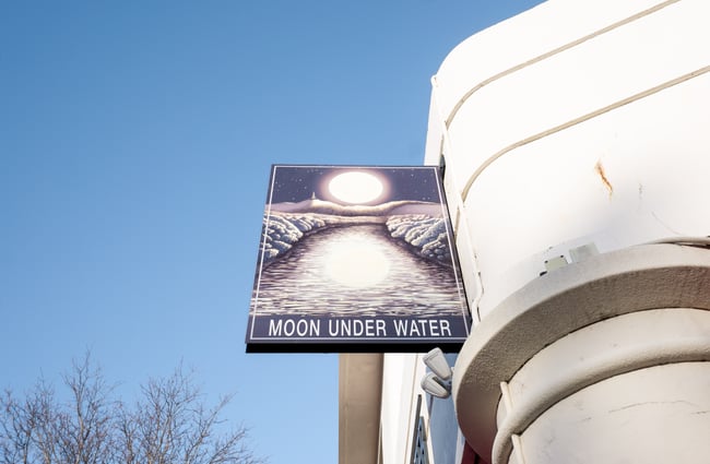 A 'Moon Under Water' sign on the exterior of a building on a sunny day.