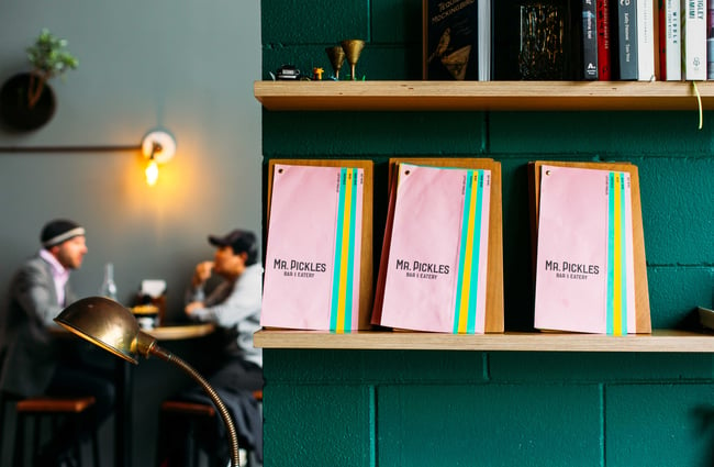 Pink menus with green striped on wooden clip boards.