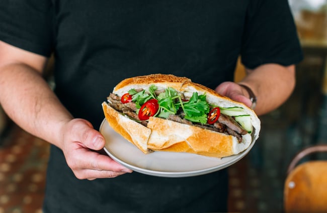 Person holding Vietnamese baguette, Bánh mì, at Mr T's Baked Goods and Eatery, Auckland.