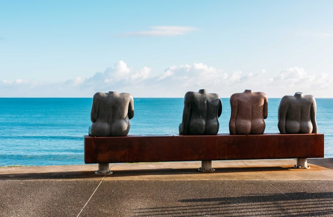 A sculpture of women sitting on a bench seat looking out to sea.